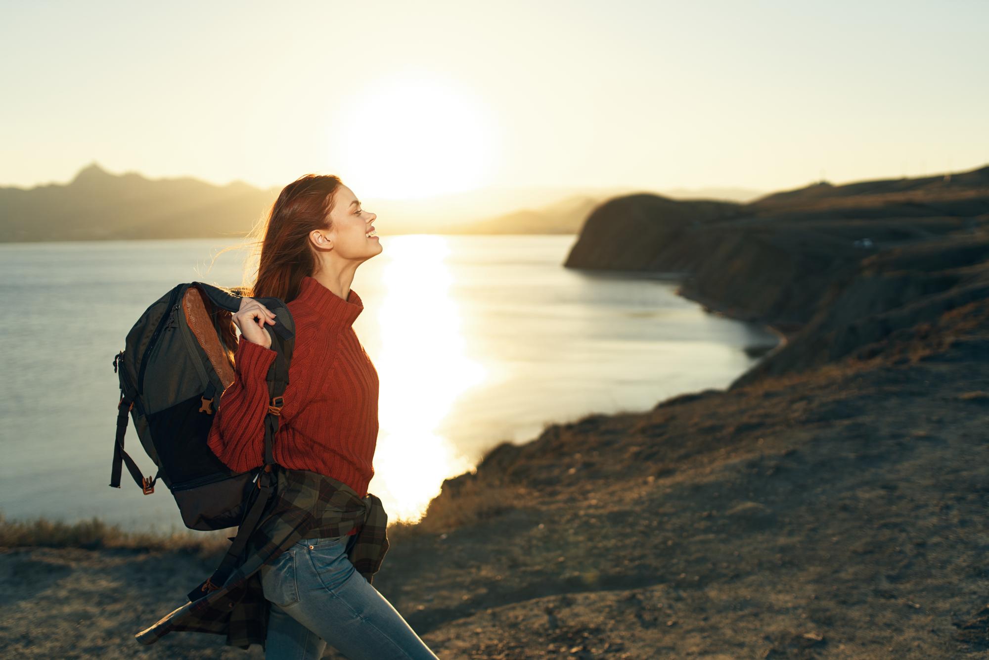 A woman traveling alone and standing by the sea at sunset