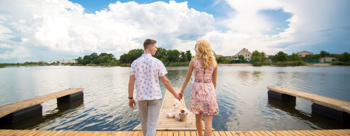 A couple on their honeymoon standing hand in hand in front of river