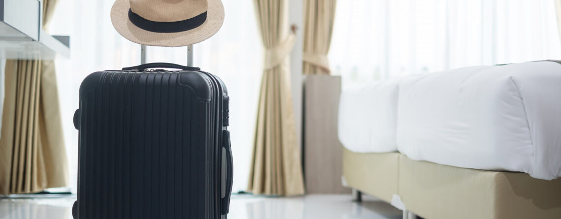 black luggage with hat in modern hotel room