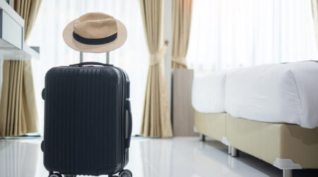 black luggage with hat in modern hotel room