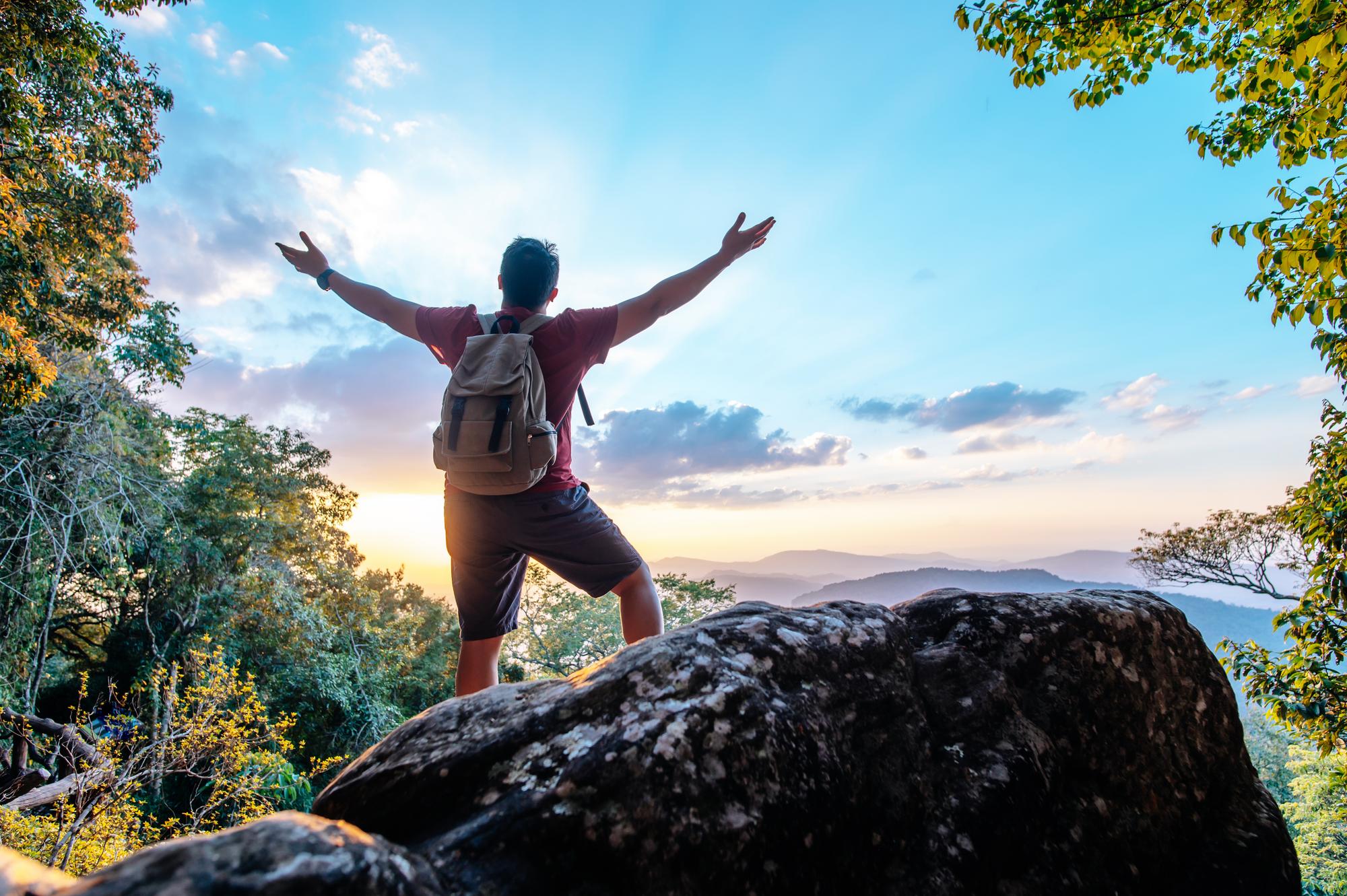 A man standing on top of a hill with open arms