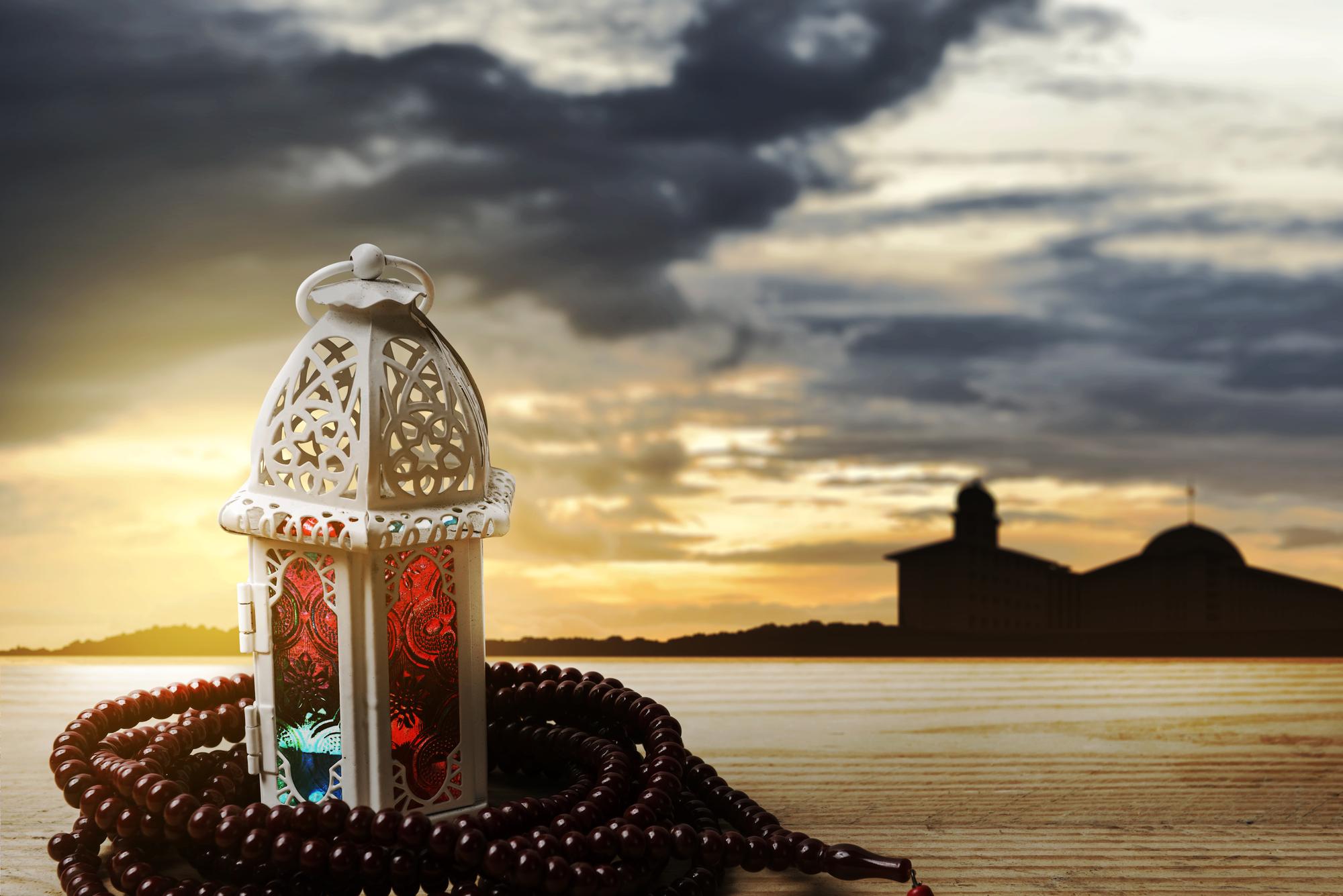 Arabic lamp with colorful light prayer beads wooden table with dramatic scene background