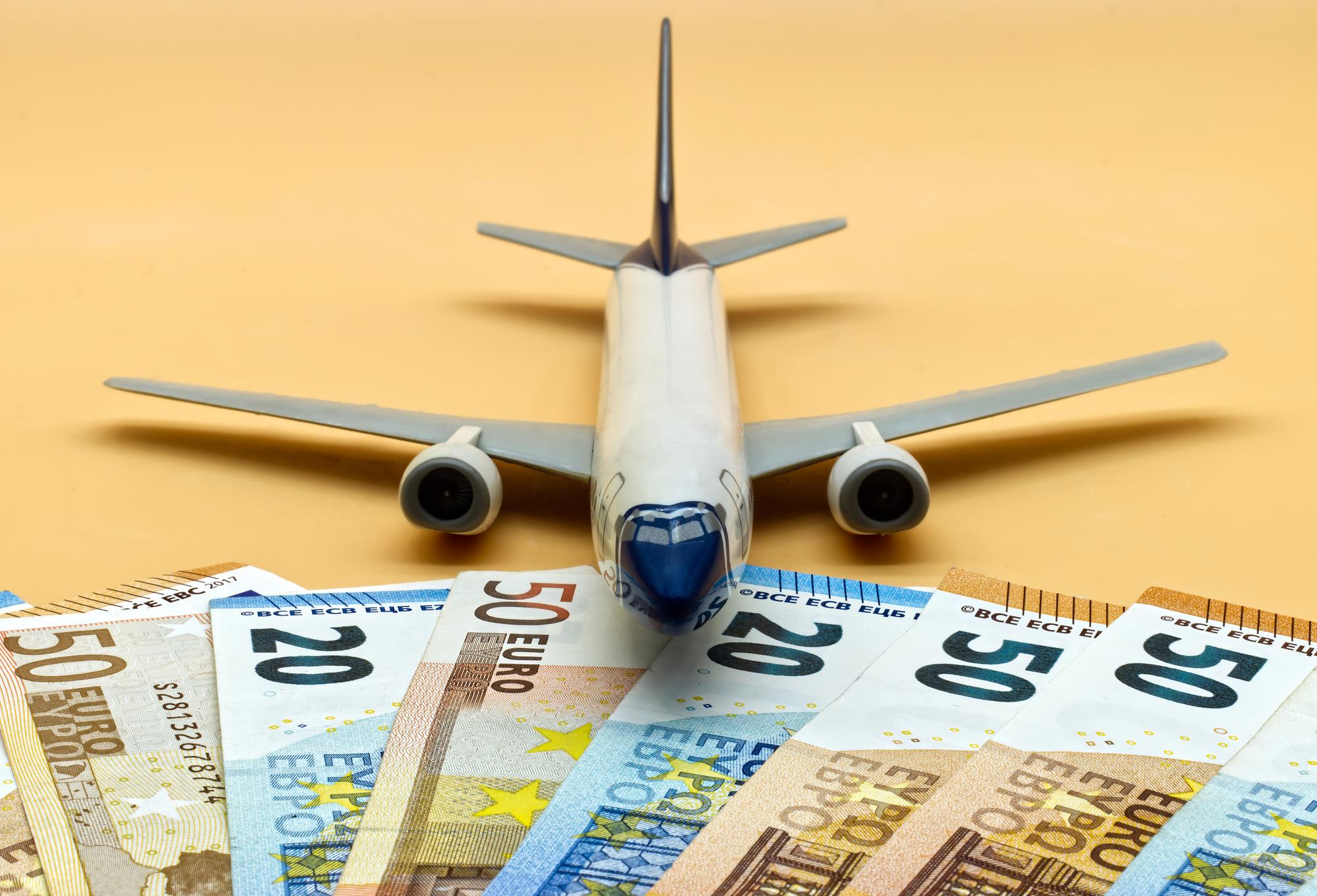 commercial airplane toy pile euro banknotes cheap flights cost concept