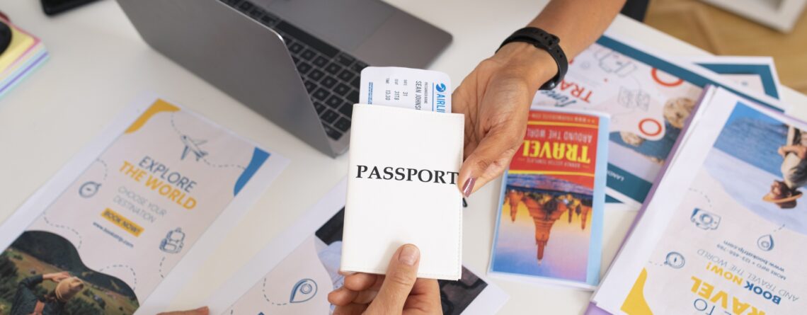 high-angle-travel-agency-desk-with-people-working-laptop-holding-passport